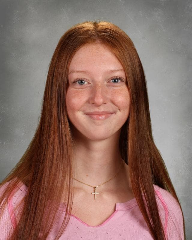Portrait of Annalise Chambers smiling with a camera strap over her shoulder