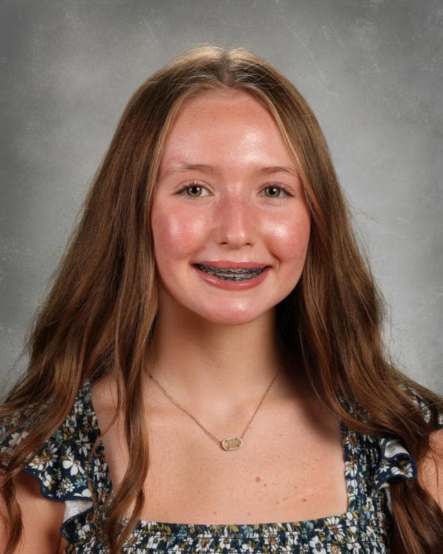 Portrait of Rosaline Wren smiling in front of studio lighting