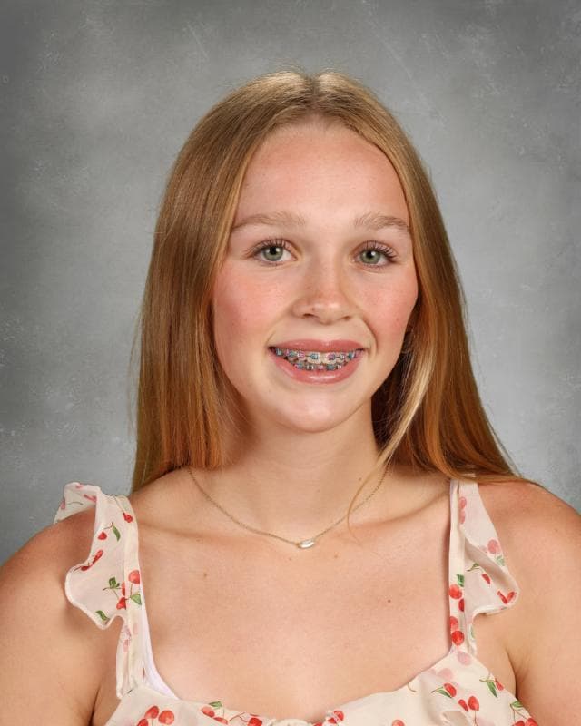 Portrait of Zoiee Ward smiling with headphones around their neck