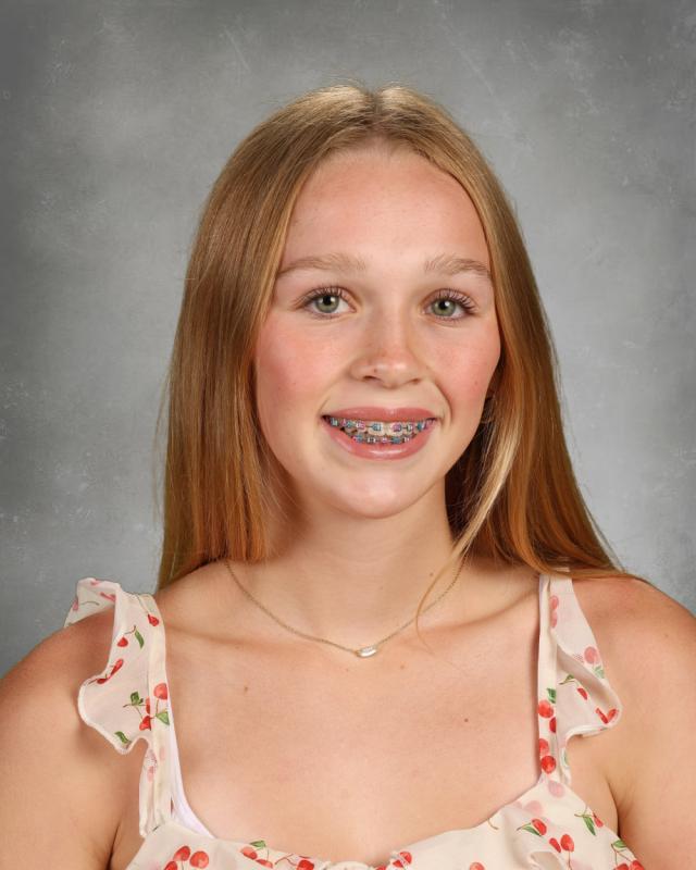 Portrait of Zoiee Ward smiling with headphones around their neck